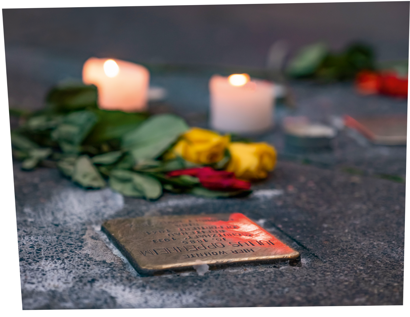 Erinnerungsstein mit Kerzen und Blumen